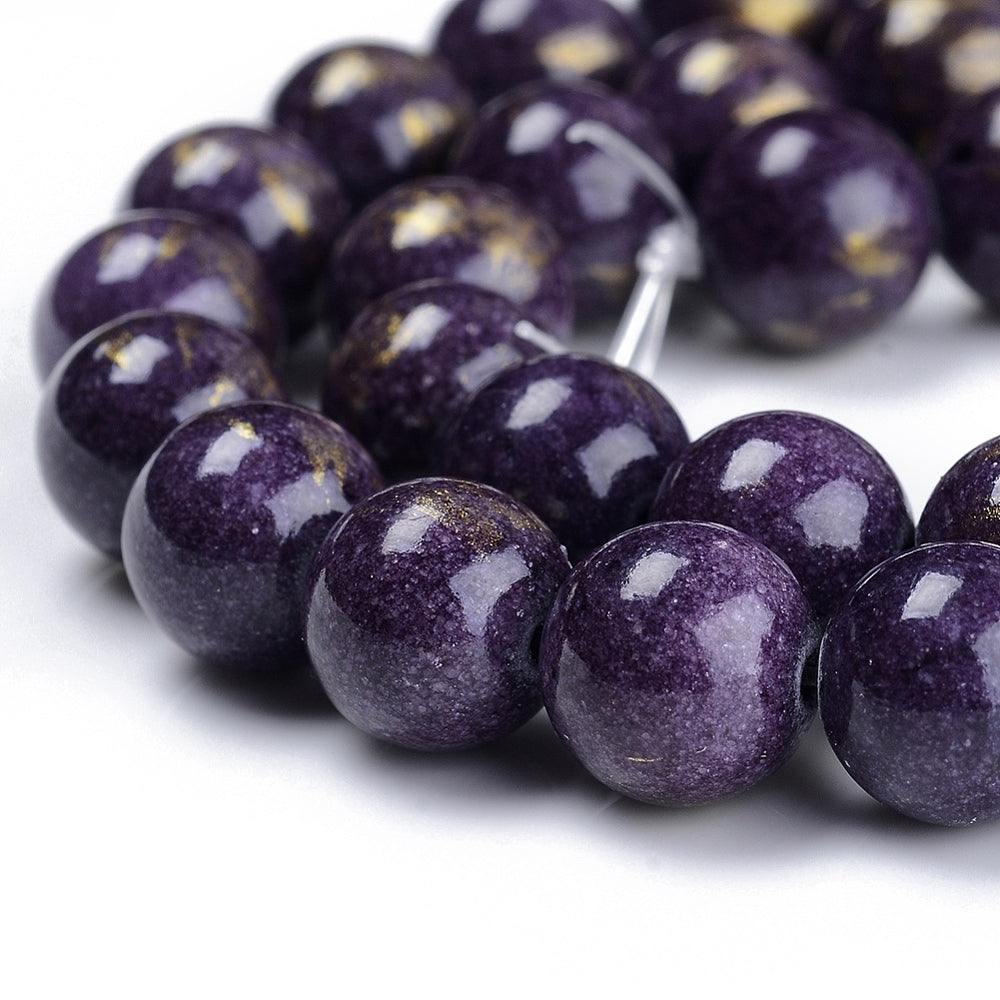 zoomed in sections of smooth round and dyed purple jade bead strands with gold foil over a white surface. 