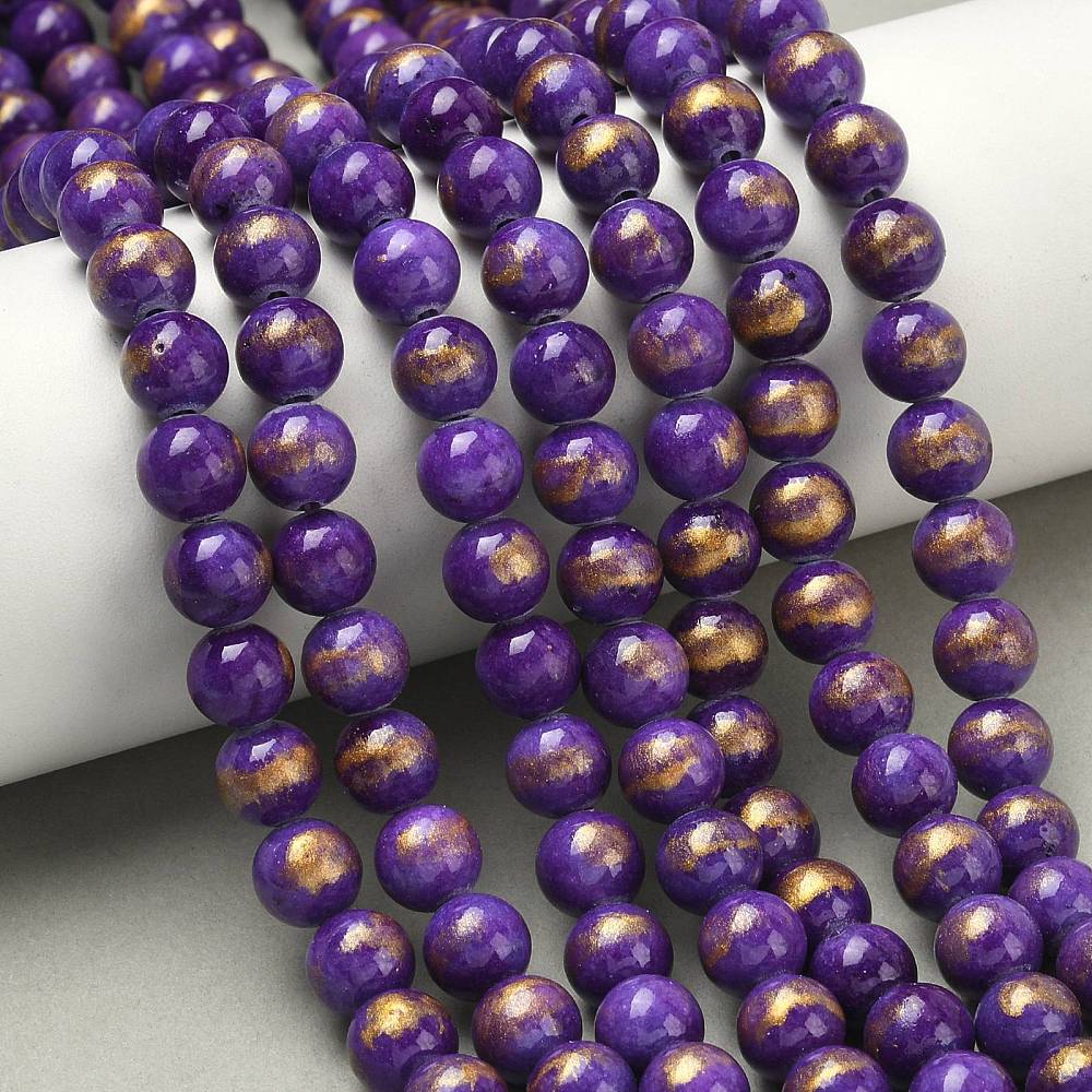 sections of smooth round and dyed purple jade bead strands with gold foil draped over a white cylinder form onto a tan surface.