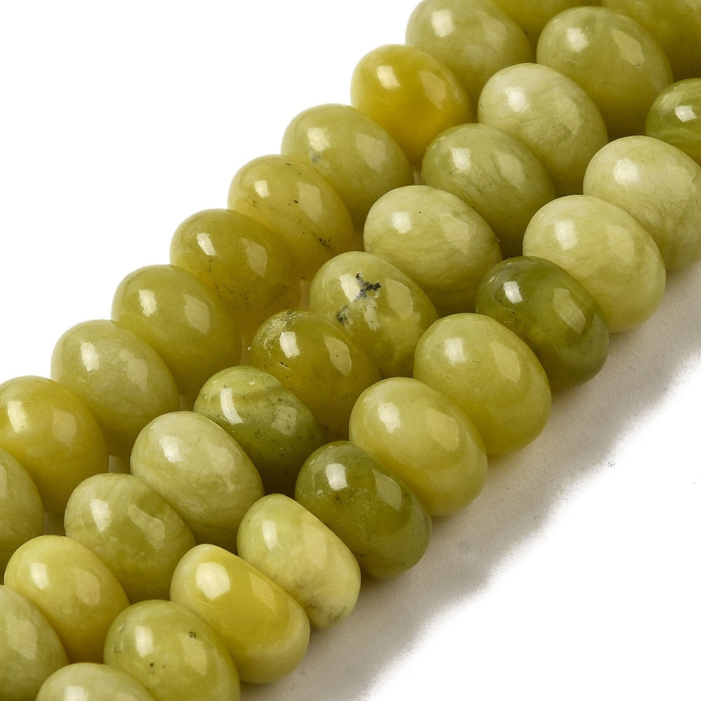 zoomed in sections of light olive dyed jade rondelle strands over white surface. 