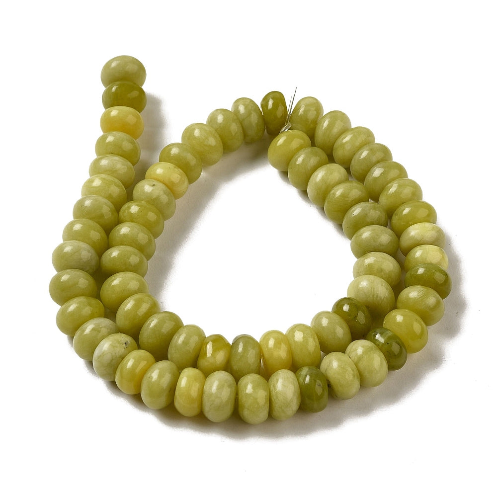 light olive dyed jade rondelle strand in swirl display over white surface. 