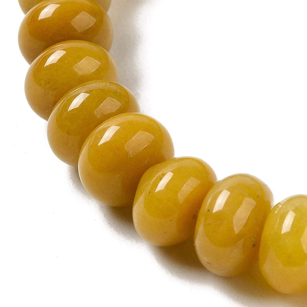 zoomed in section of assorted dark  yellow dyed jade rondelle strand over white surface.