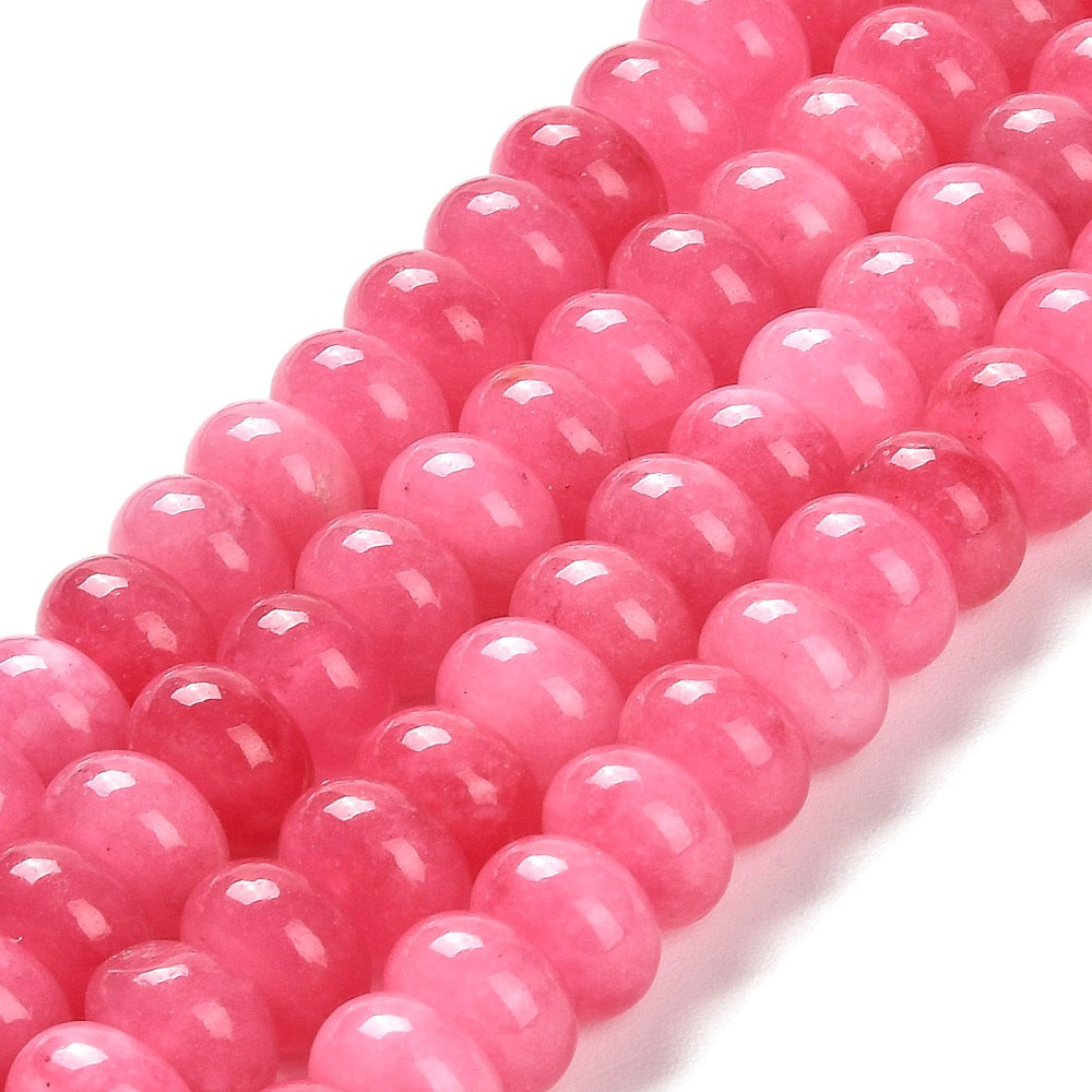 zoomed in sections of pink dyed jade rondelle strands over white surface. 