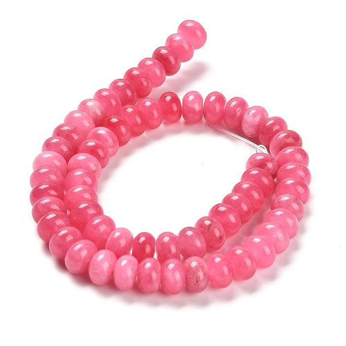 pink dyed jade rondelle strand in swirl display over white surface. 