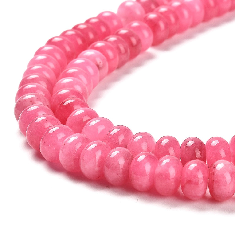 zoomed in sections of pink dyed jade rondelle strand over white surface.