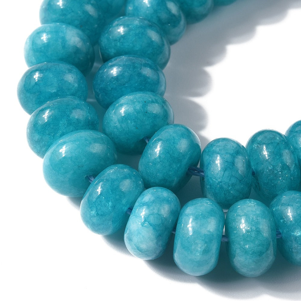 zoomed in sections of teal dyed jade rondelle strand over white surface.