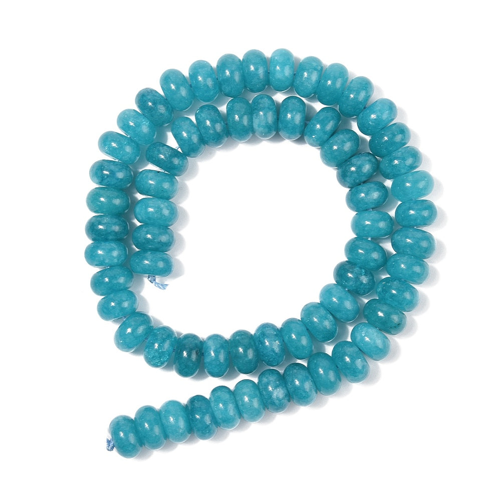 teal dyed jade rondelle strand in swirl display over white surface. 