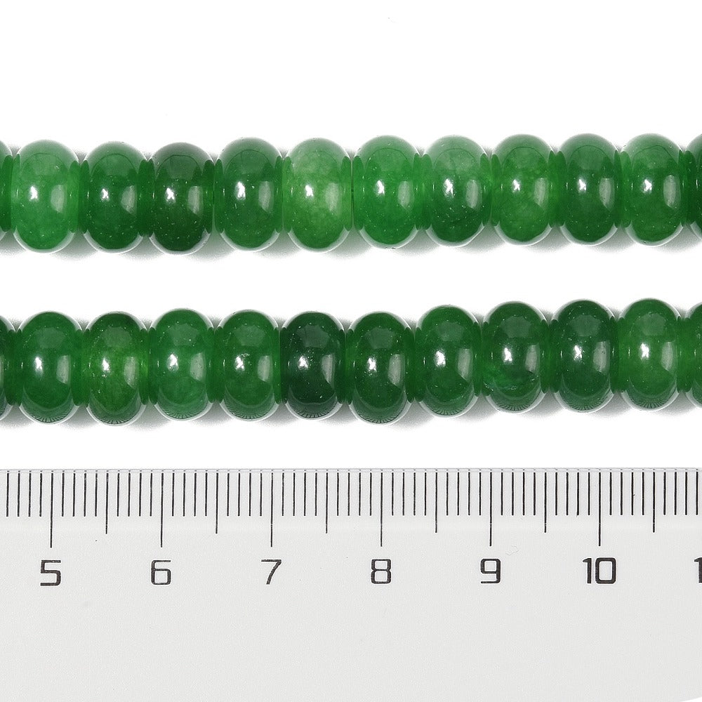 zoomed in sections of dark green dyed jade rondelle strand above clear ruler over white surface. 