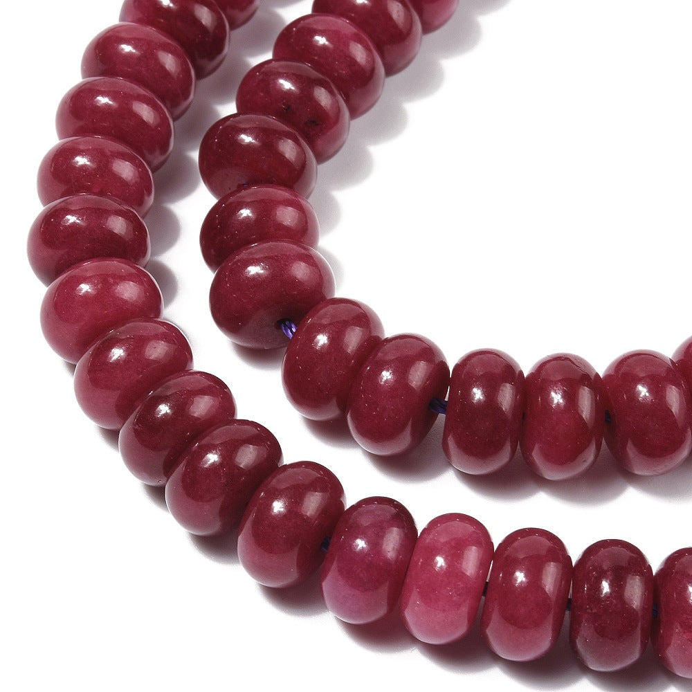 zoomed in section of dark red dyed jade rondelle strand over white 