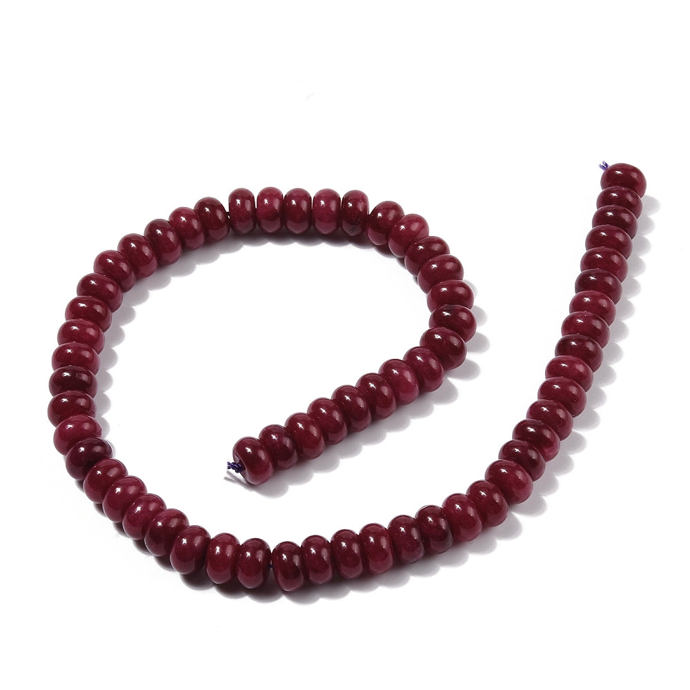 dark red dyed jade rondelle strand in swirl display over white surface. 