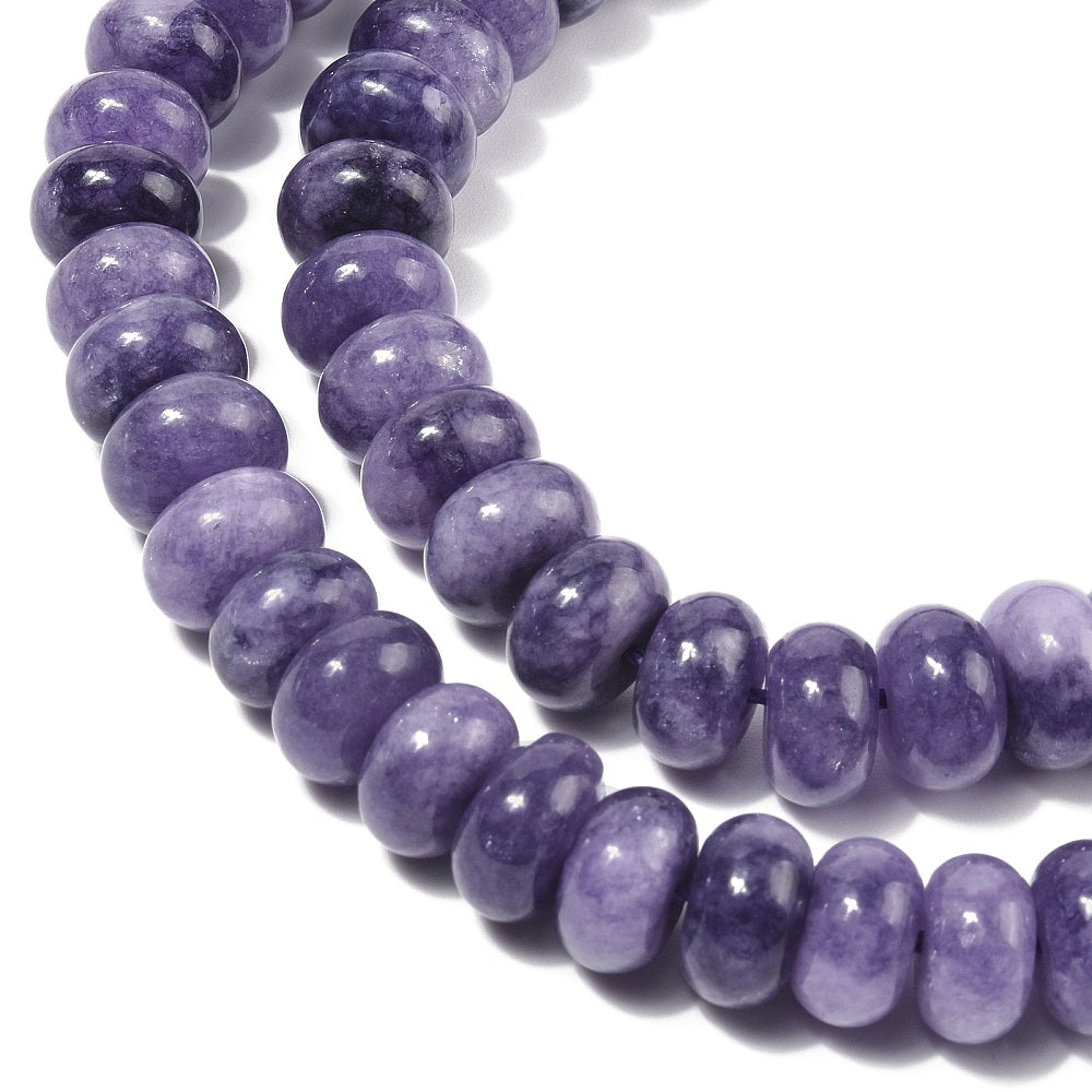 zoomed in sections of light purple dyed jade rondelle strand over white surface.