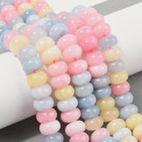 multicolor pastel smooth rondelle jade bead strands draped over white cylinder above grey felt surface.   