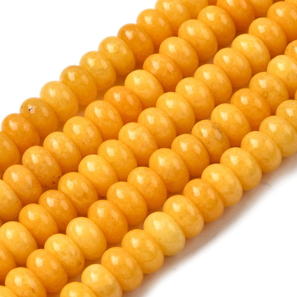 zoomed in sections of yellow dyed jade rondelle strands over white surface. 