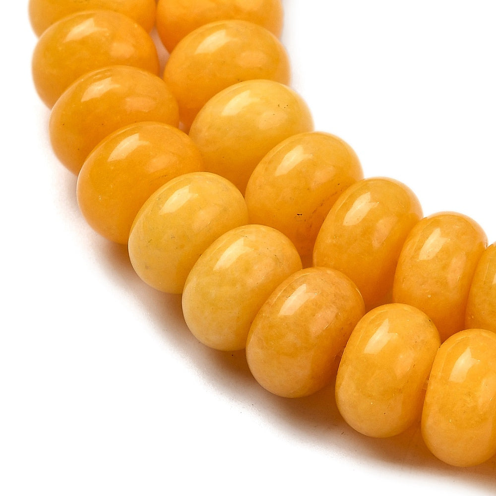 zoomed in sections of yellow dyed jade rondelle strand over white surface. 