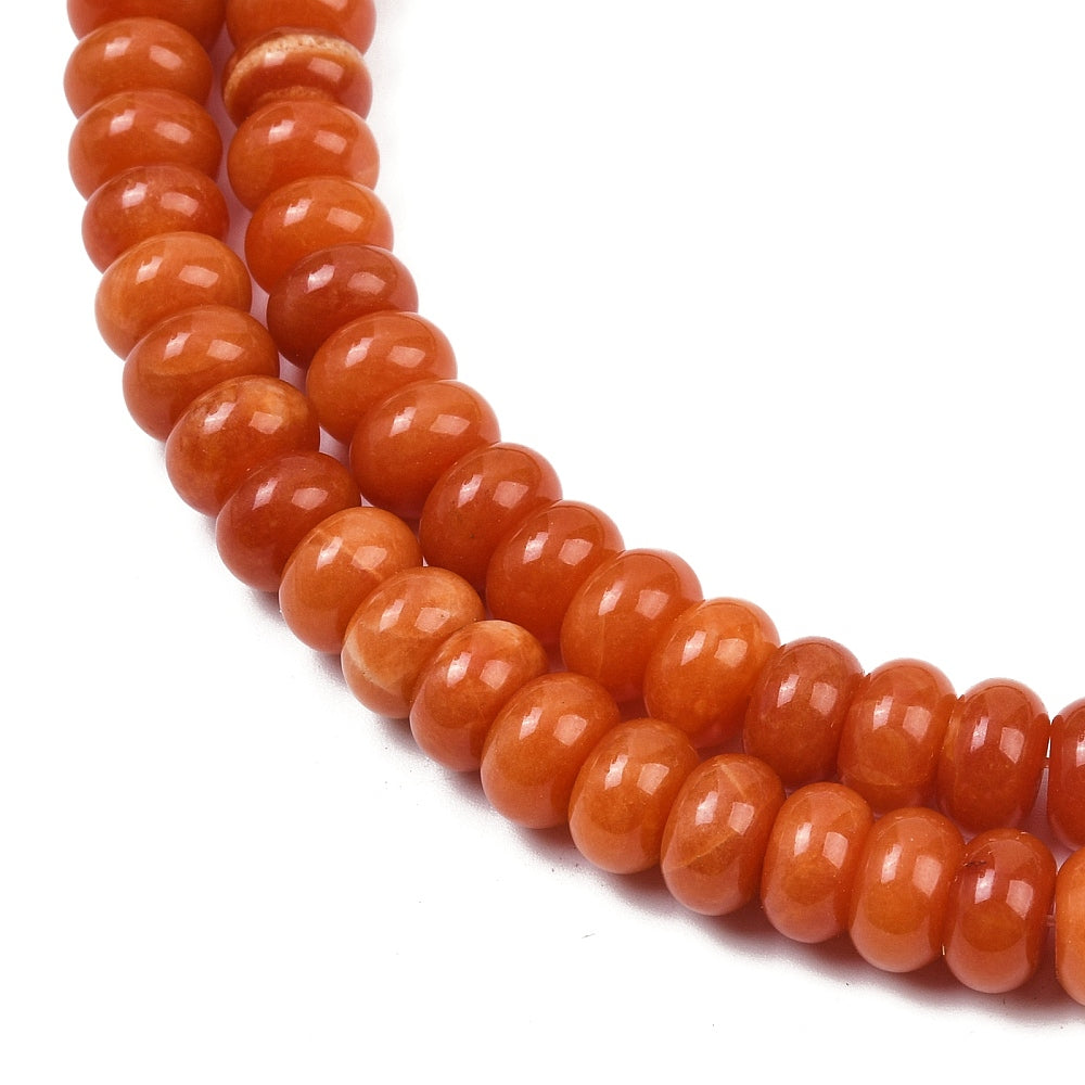 zoomed in section of orange dyed jade rondelle strand over white 