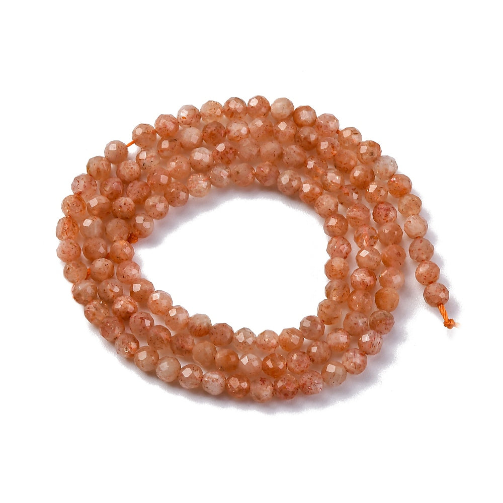 faceted round sunstone bead strand in swirl design over white background.