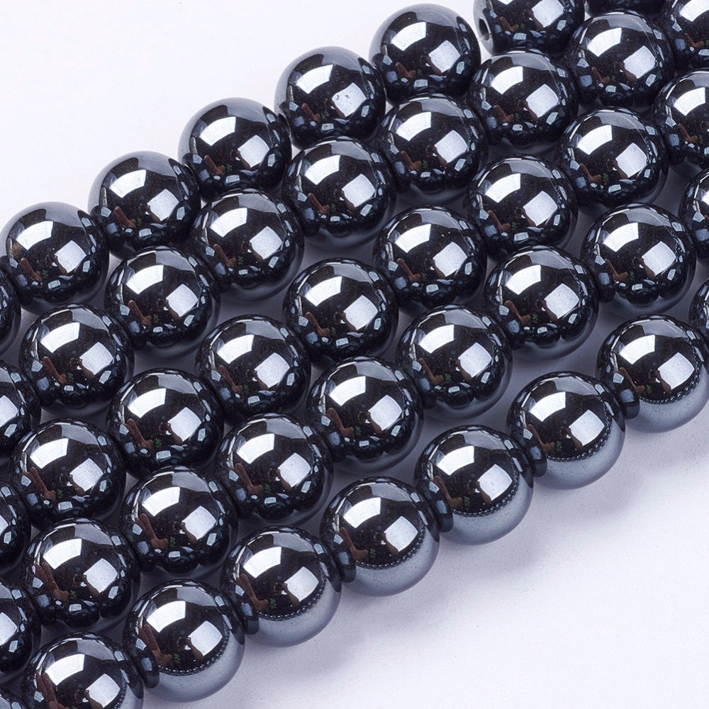 zoomed in sections of round hematite bead strands over white surface. 