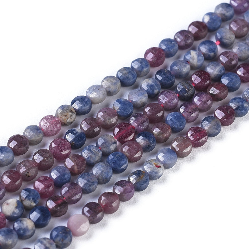 close-up of faceted coin shaped natural ruby and sapphire bead strands over white background. 