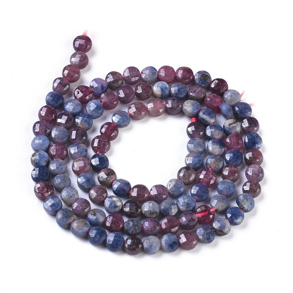 faceted coin shaped natural ruby and sapphire bead strand in swirl design over white background. 