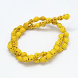 yellow skull carved stone bead strand over white background. 