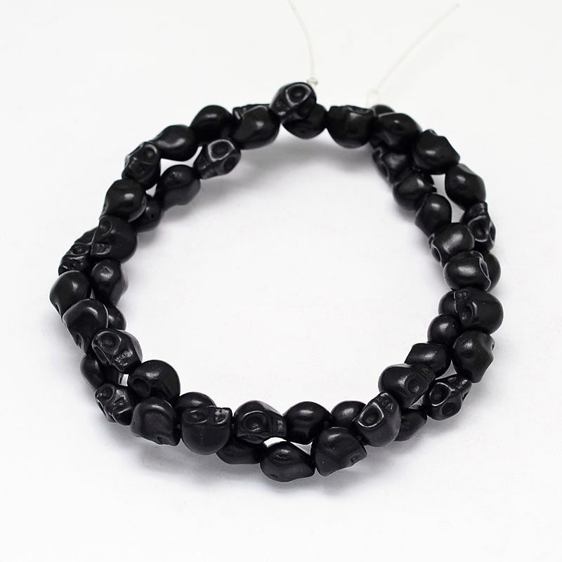 black skull carved stone bead strand on white background. 
