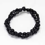black skull carved stone bead strand on white background. 