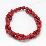 red skull carved stone bead strand over white background. 
