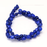 blue skull carved stone bead strand over white background. 
