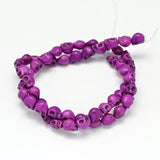 magenta skull carved stone bead strand over white background. 