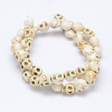 off white skull carved stone bead strand over white background. 