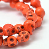 zoomed in section of orange skull carved stone bead strand over white background. 