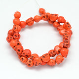 orange skull carved stone bead strand over white background. 