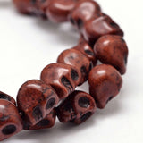 zoomed in section of brown skull carved stone bead strand on white background. 