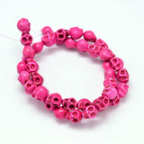 pink skull carved stone bead strand on white background. 