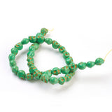 green skull carved stone bead strand over white background. 