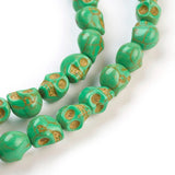 zoomed in section of green skull carved stone bead strand over white background. 