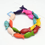 multicolor dyed magnesite fish bead strand in swirl design over white background. 