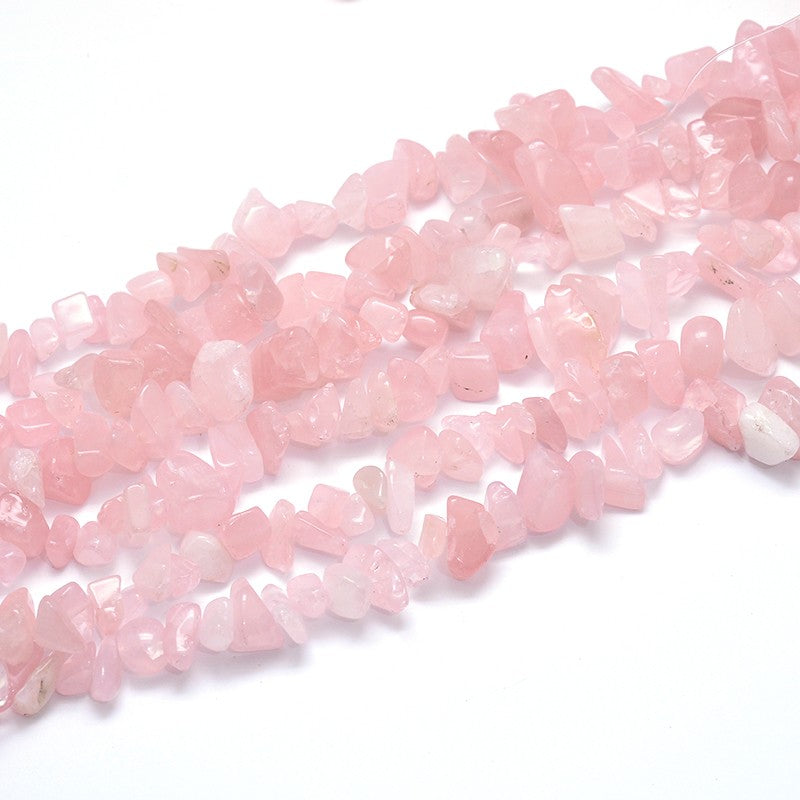 six tumbled rose quartz large chip strands over white background. 