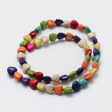 multicolor dyed magnesite heart stone bead strand in swirl design over white background. 