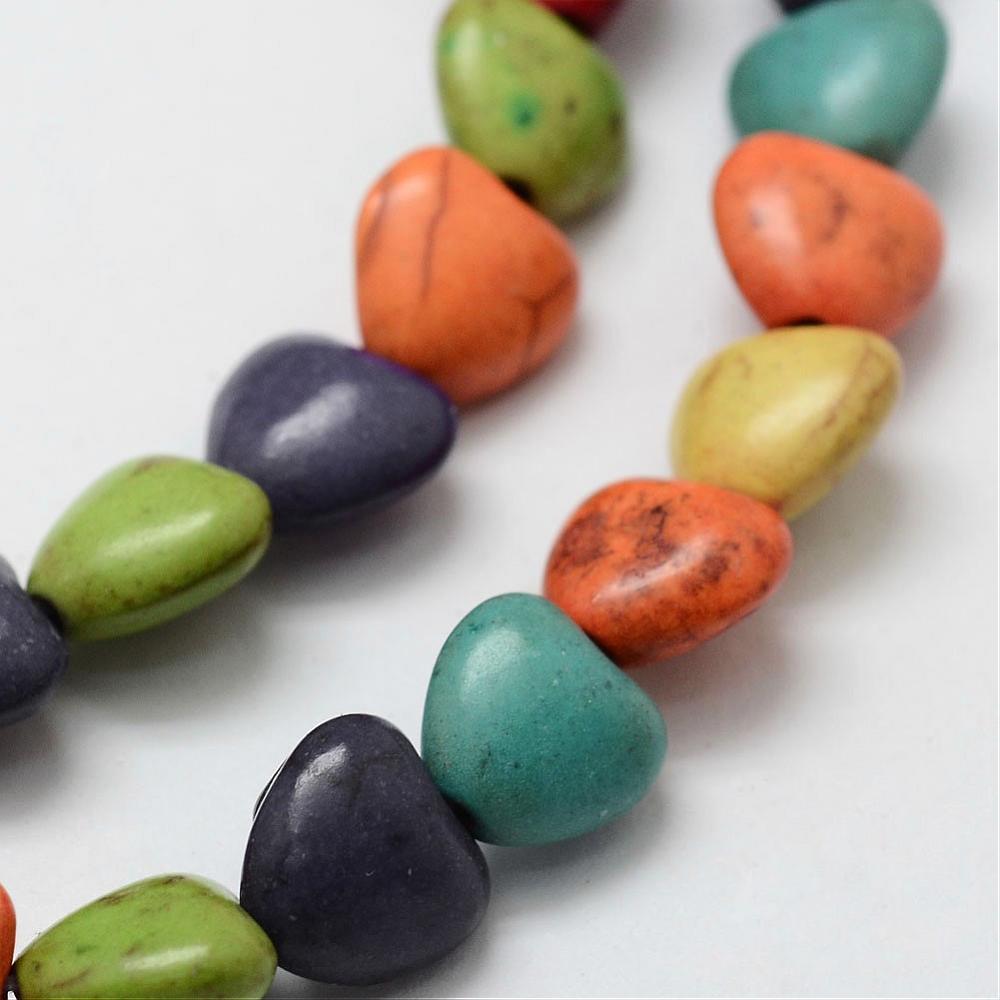 zoomed in section of multicolor dyed magnesite heart stone beads over white background. 