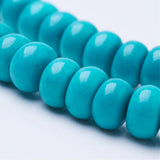 zoomed in sections of two dyed turquoise magnesite rondelle bead strands over white background. 