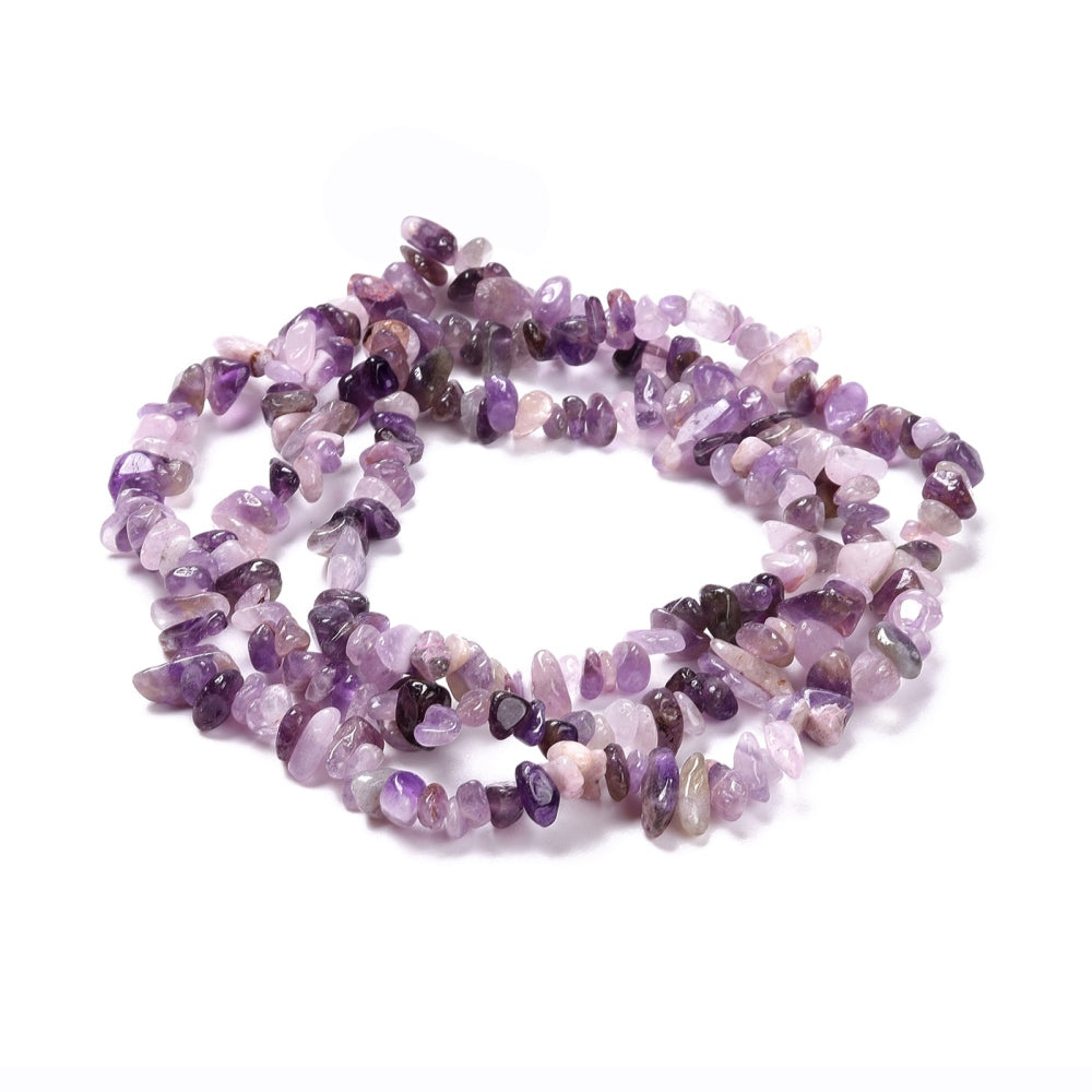 light purple tumbled amethyst chip bead strand in swirl design over white surface. 