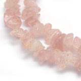 zoomed in section of multiple light pink rose quartz chip strands over white background. 
