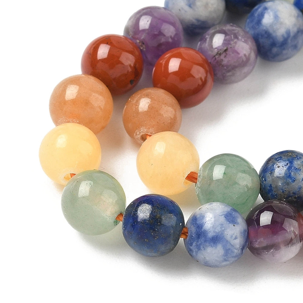 zoomed in sections of natural mixed gemstone chakra bead strand white surface. 