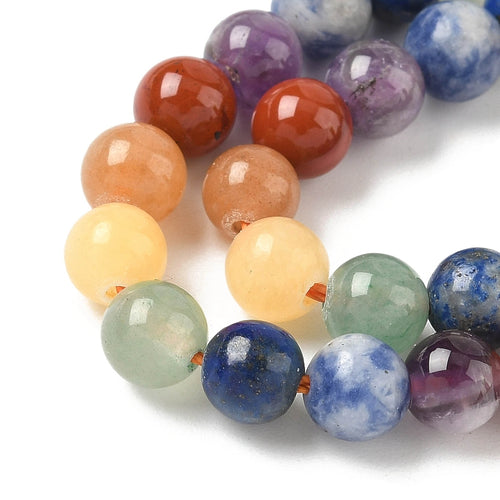 zoomed in sections of natural mixed gemstone chakra bead strand white surface. 