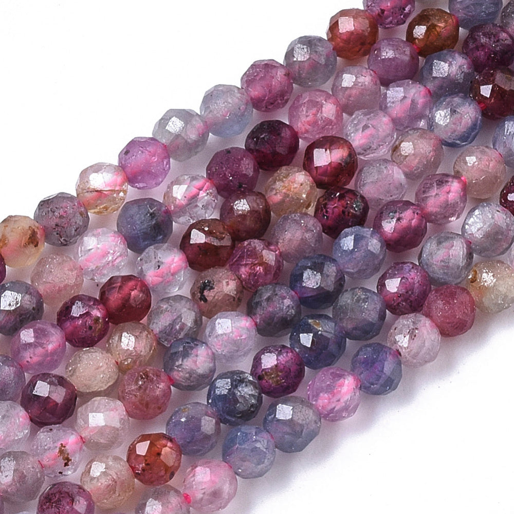 close-up of multicolor faceted round spinel bead strands over white background. 