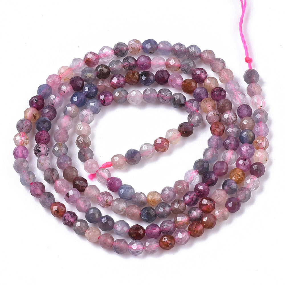 multicolor faceted round spinel bead strand in swirl design over white background. 