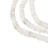 zoomed in sections of three clear quartz faceted cube bead strands over white background. 