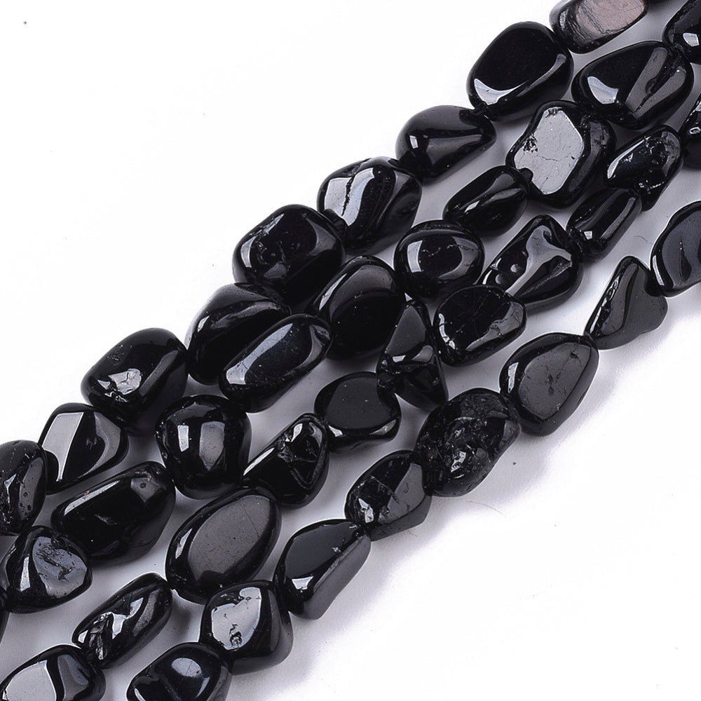 four strands of tumbled black tourmaline nugget beads over white background. 