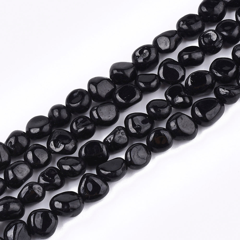 four strands of tumbled black tourmaline nugget beads over white background. 