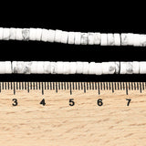 two zoomed in sections of natural Howlite Heishi bead strands displayed above a wooden ruler over a black background. 